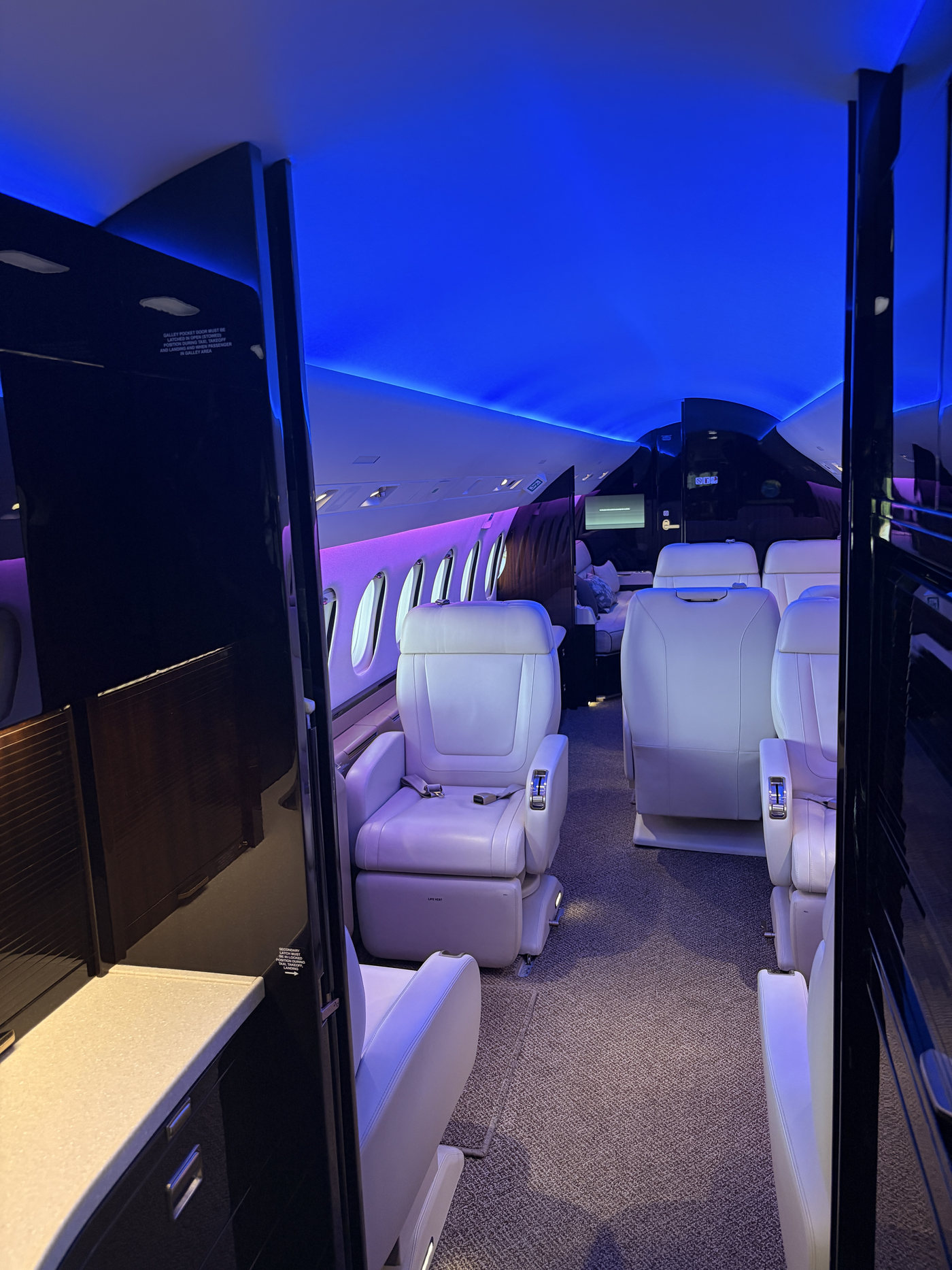 Business jet cabin aisle lit in blue and purple mood lighting