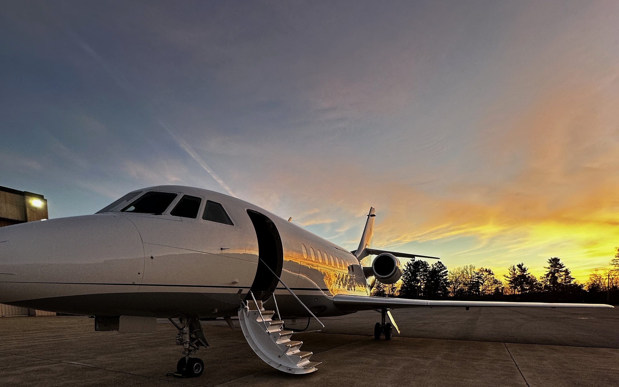 Dassault Falcon business jet with the airstair down on the ramp at sunset